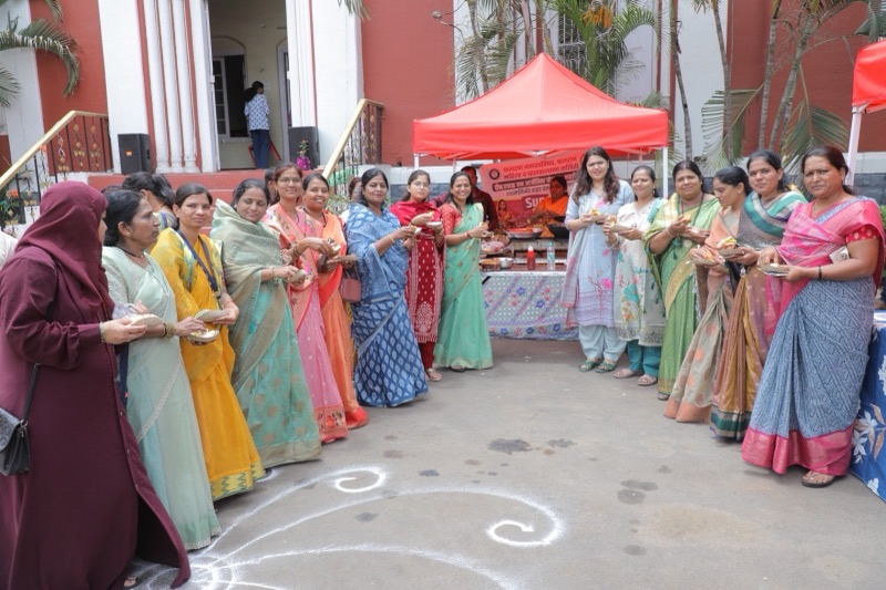 Women in colourful sarees gathered outdoors for a community programme
