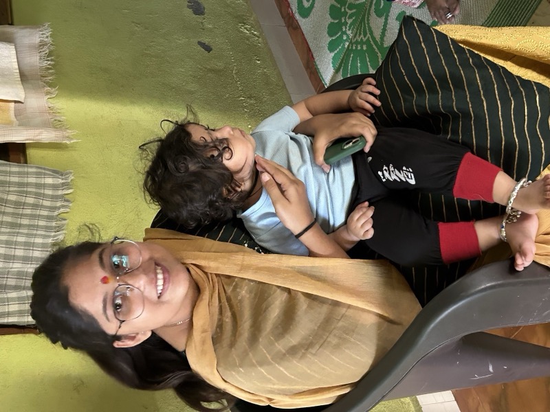 Siddhali Anup Shah smiling while holding a young child during a community visit