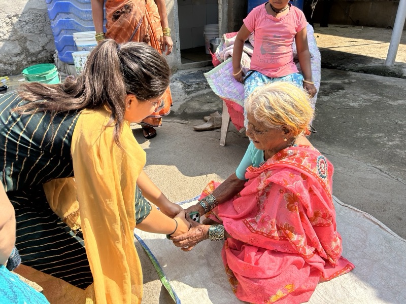 Siddhali Anup Shah holding an elderly woman’s hands during a visit