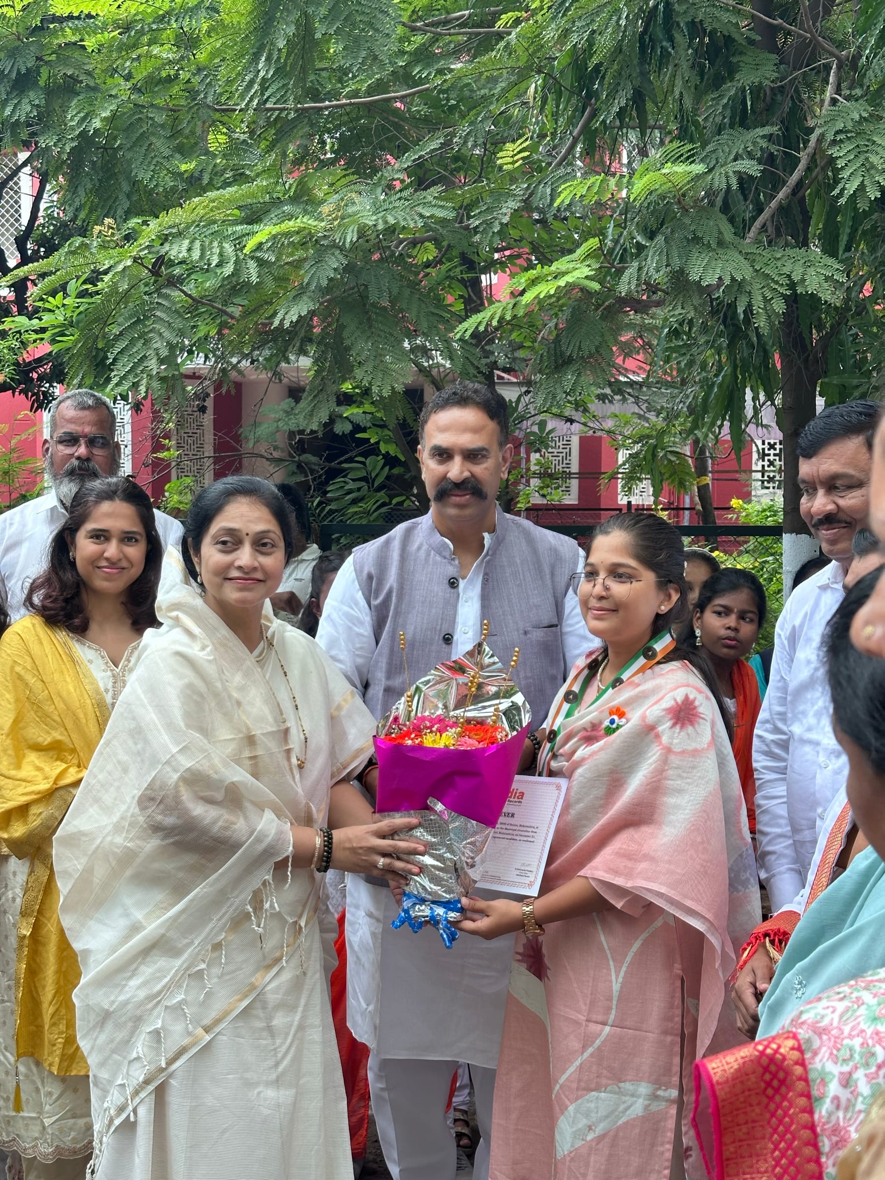 Siddhali Anup Shah receiving flowers at a community gathering.